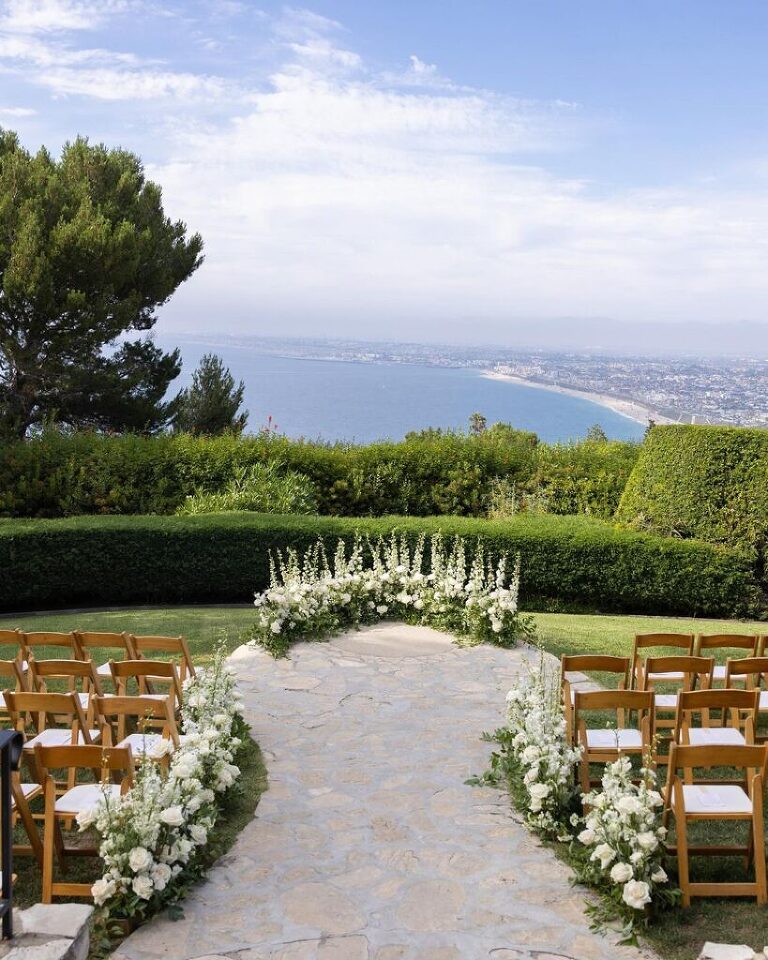 Sprays of white florals along an outdoor wedding ceremony aisle at La Venta Inn.